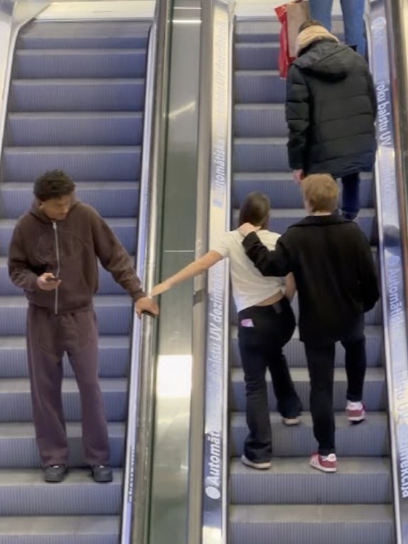 Two escalators: a hand reaches across to a stranger for help