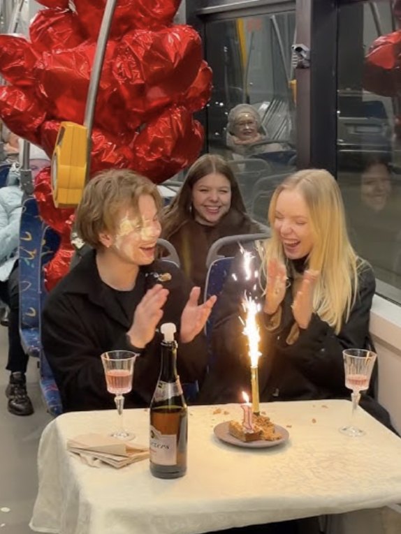 A birthday table with a sparkler and red balloons set up inside a tram