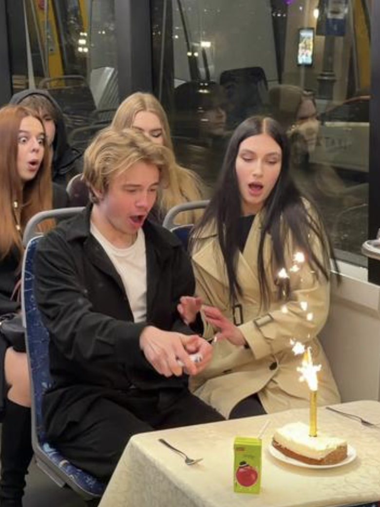 Lighting a sparkler on a cake in a tram while passengers gasp